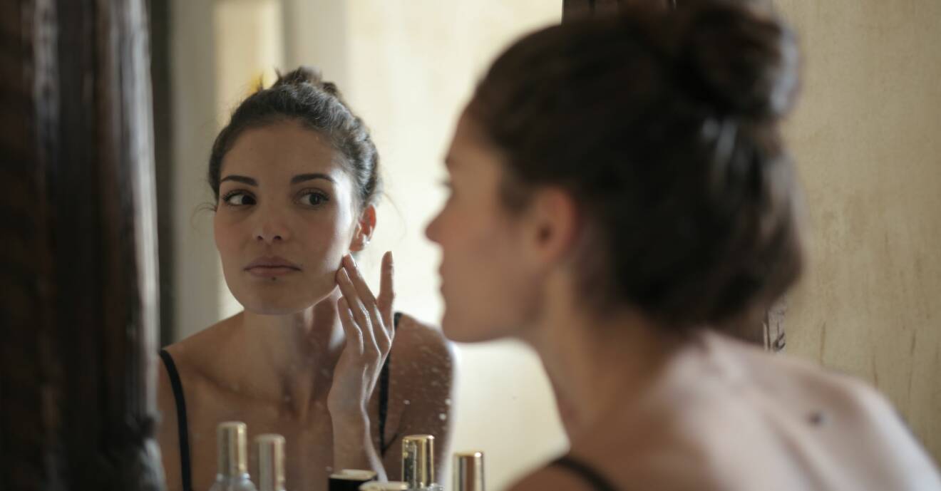 kvinna som kollar huden i spegeln