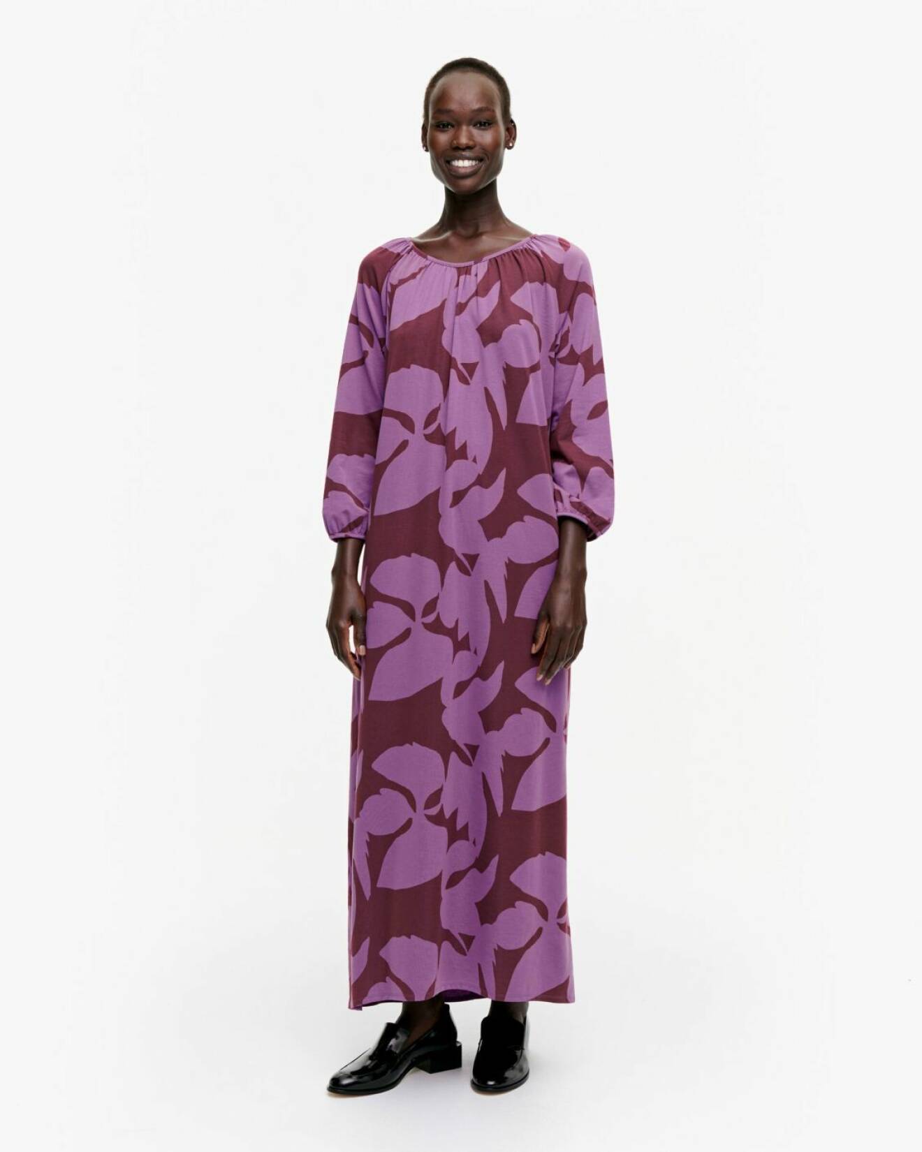 Modell med maxiklänning/kaftan i vinrött med lila blommönster på. Klänning från Marimekko.