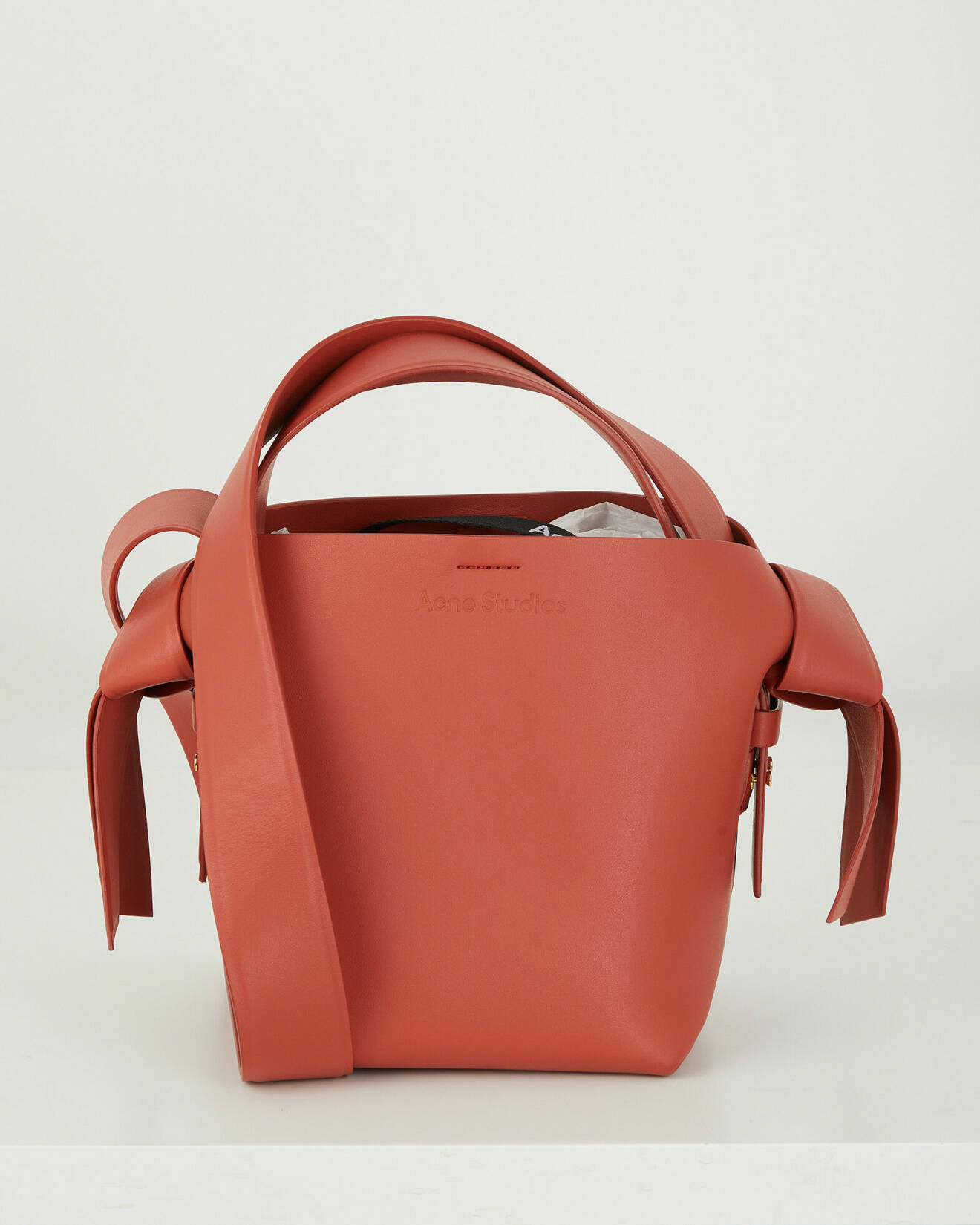 Röd väska i skinn från Acne. Väskan har en lång axelrem och ett kortare handtag.