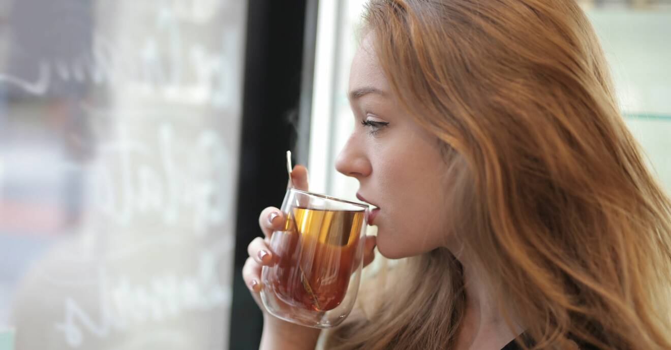Kvinna med vackert hår dricker te