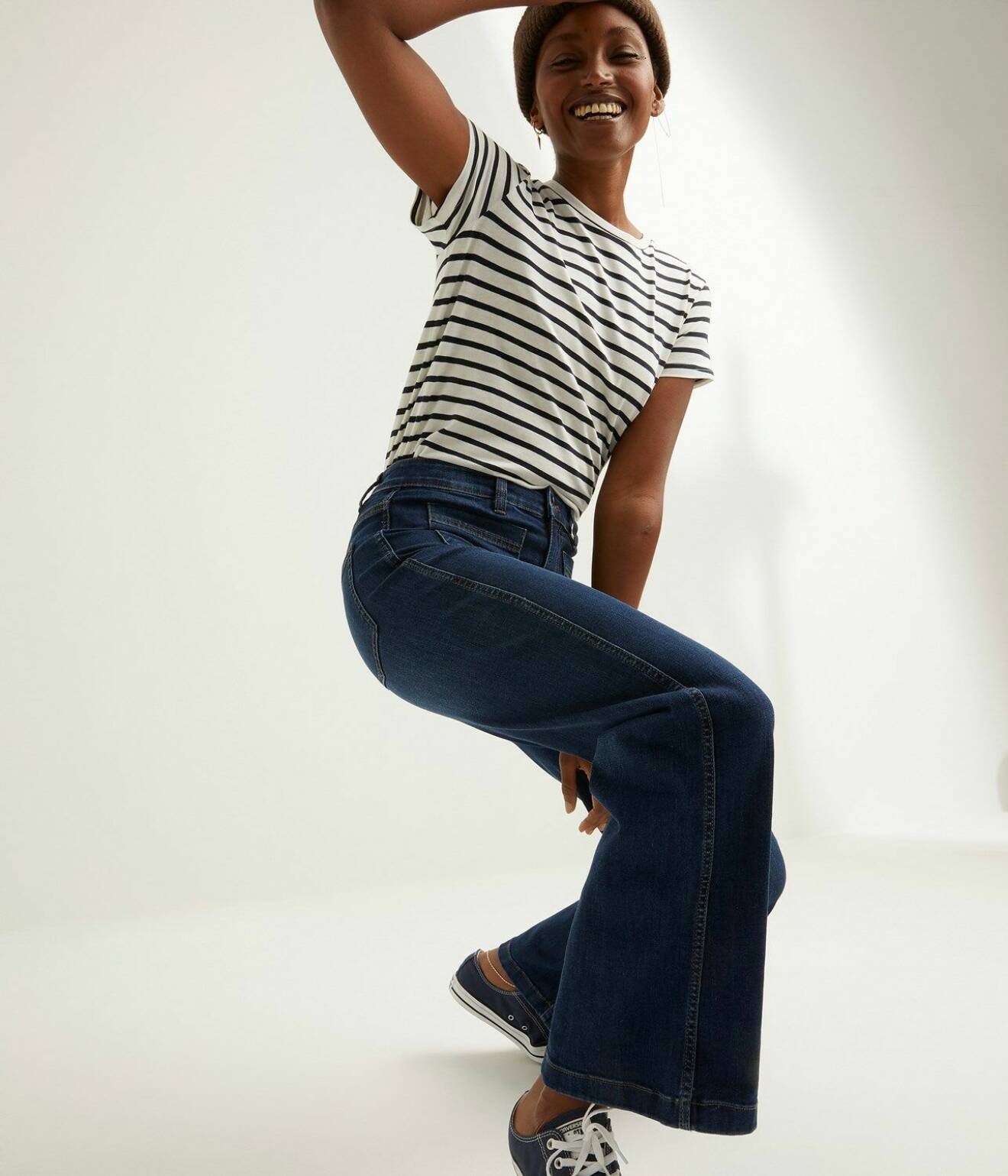 Modell med blå, utställda jeans och randig t-shirt i svart och vitt. Outfit från Kappahl.
