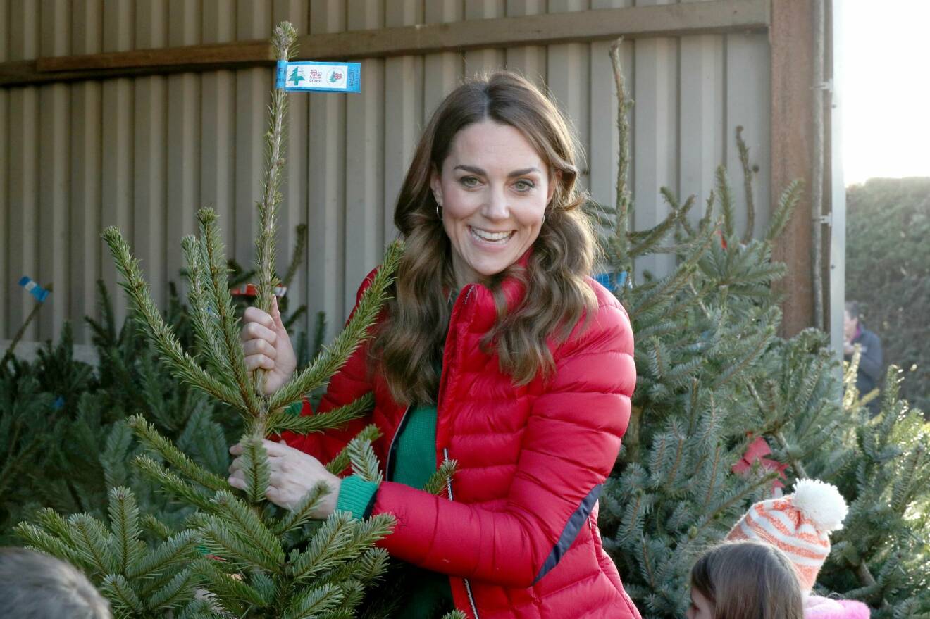 Kate hämtar julgranar klädd i en röd dunjacka.