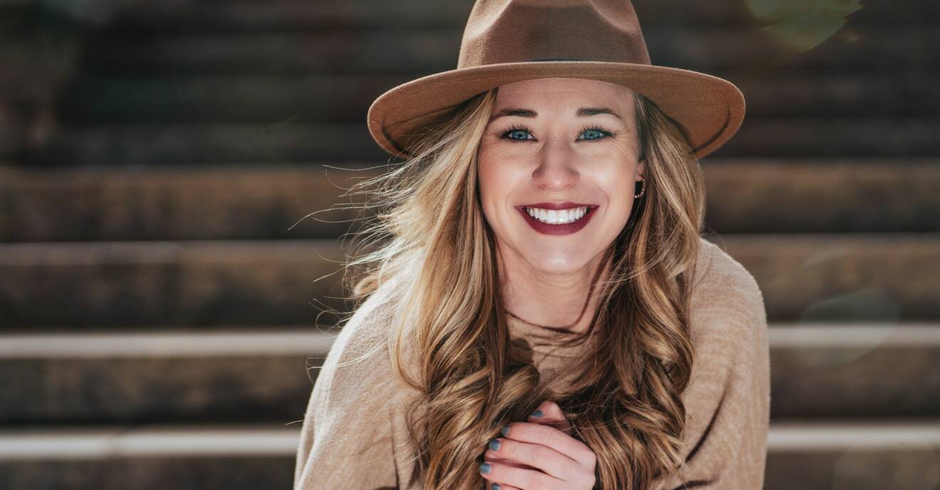 kvinna med hatt, röda läppar och vitt leende
