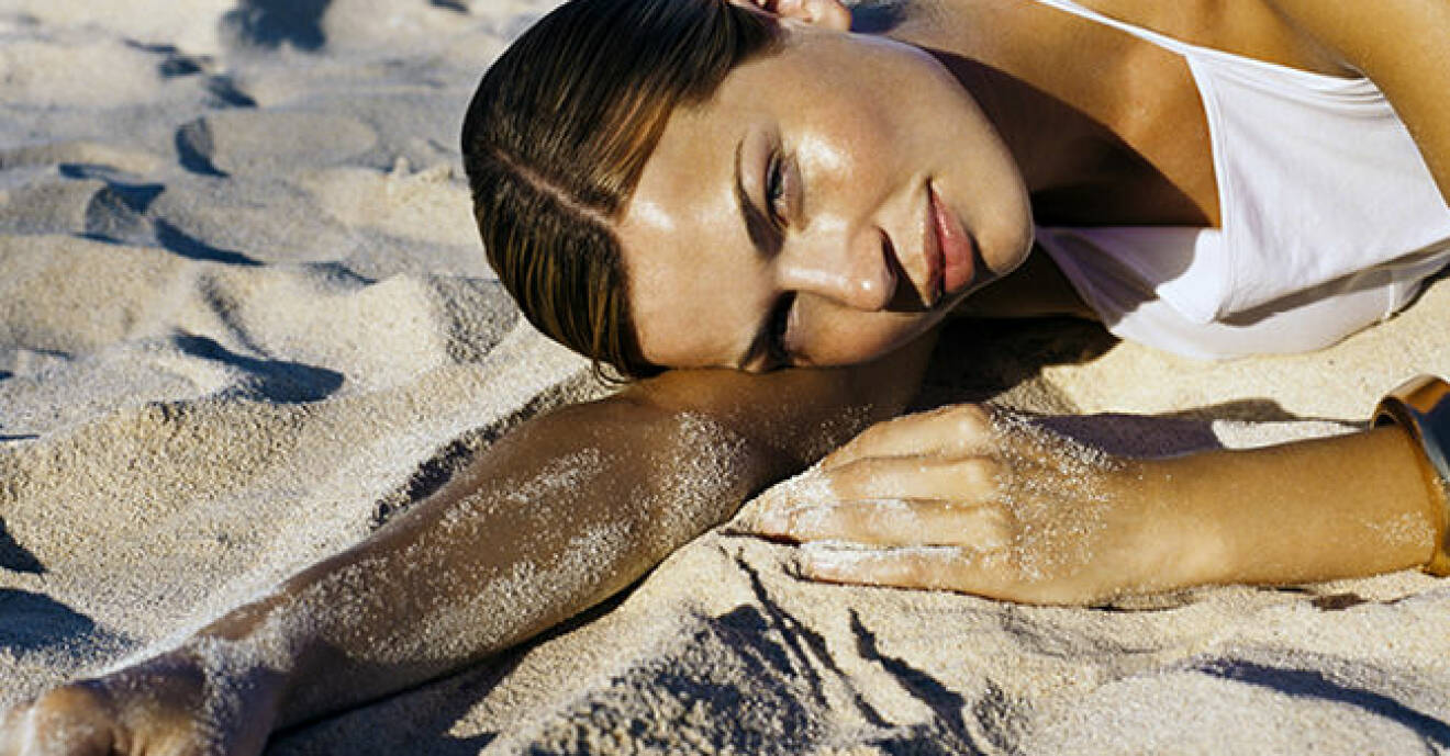 kvinna ligger i sanden på stranden