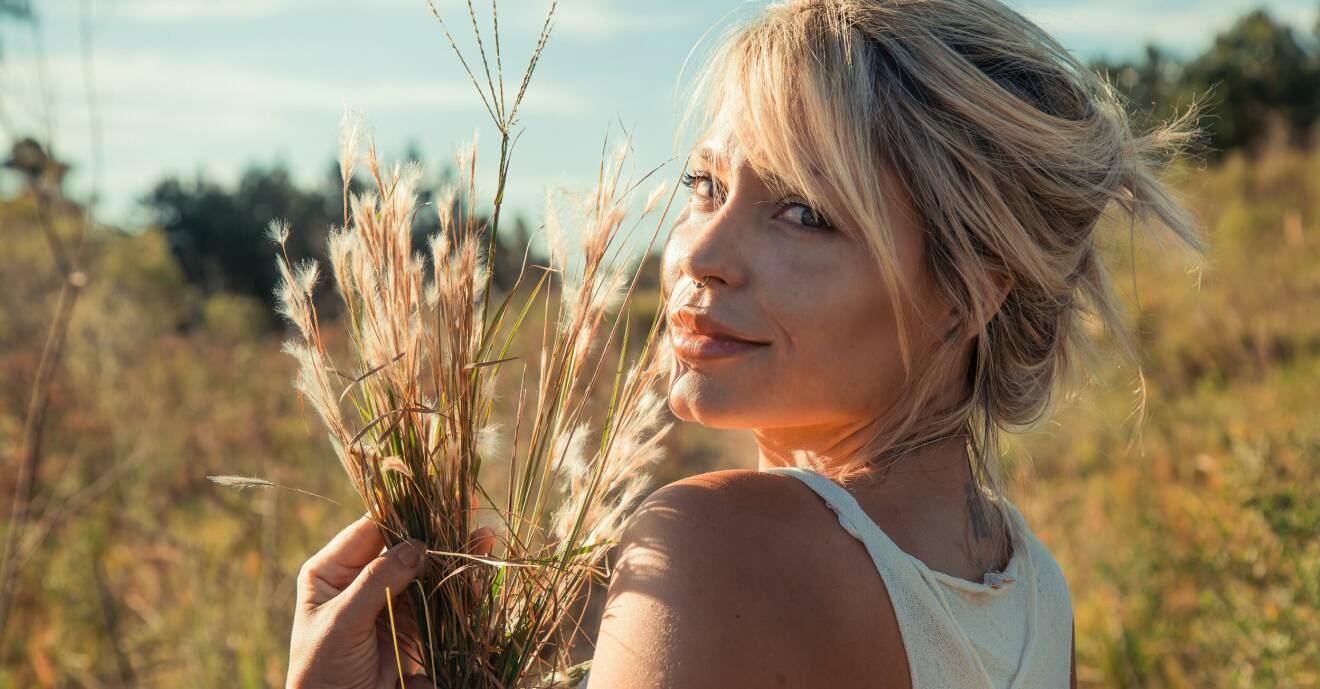 kvinna på sädesfält med solen i ansiktet