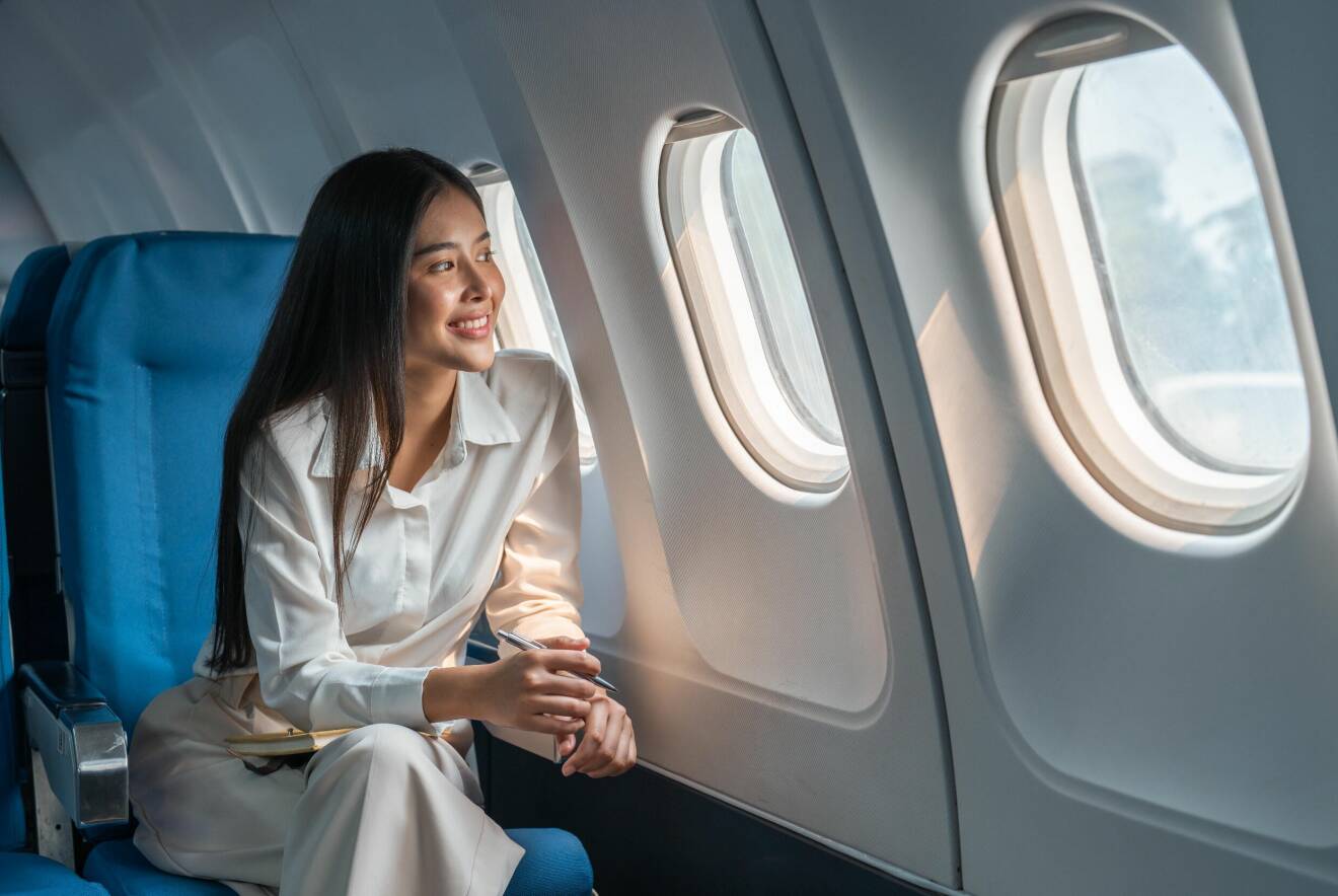 kvinna tittar ut genom fönstret på ett flygplan.