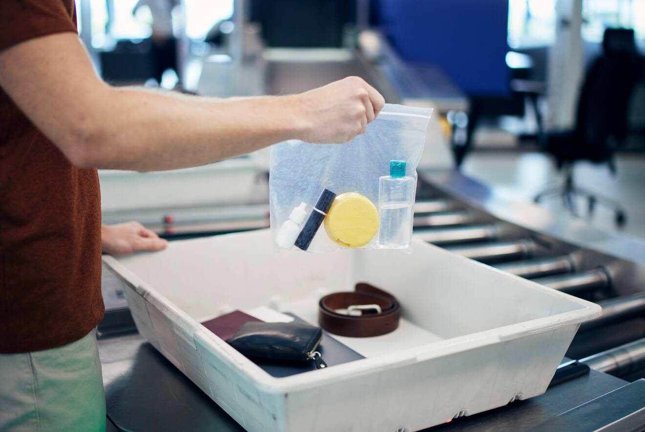 man går igenom security control på en flygplats och har lagt sina vätskor i en genomskinlig plastpåse