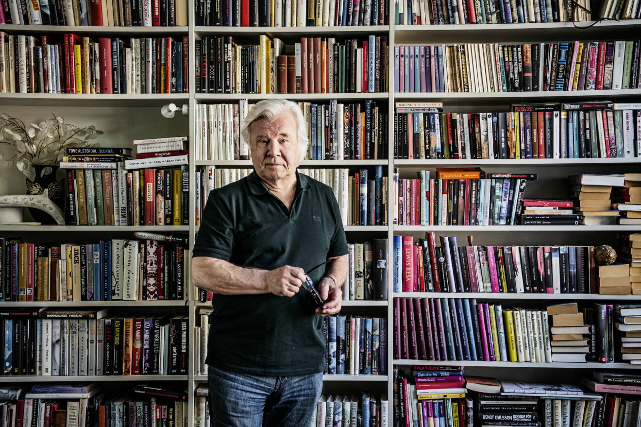 Författaren Jan Gulliou framför sin egen välfyllda bokhylla.