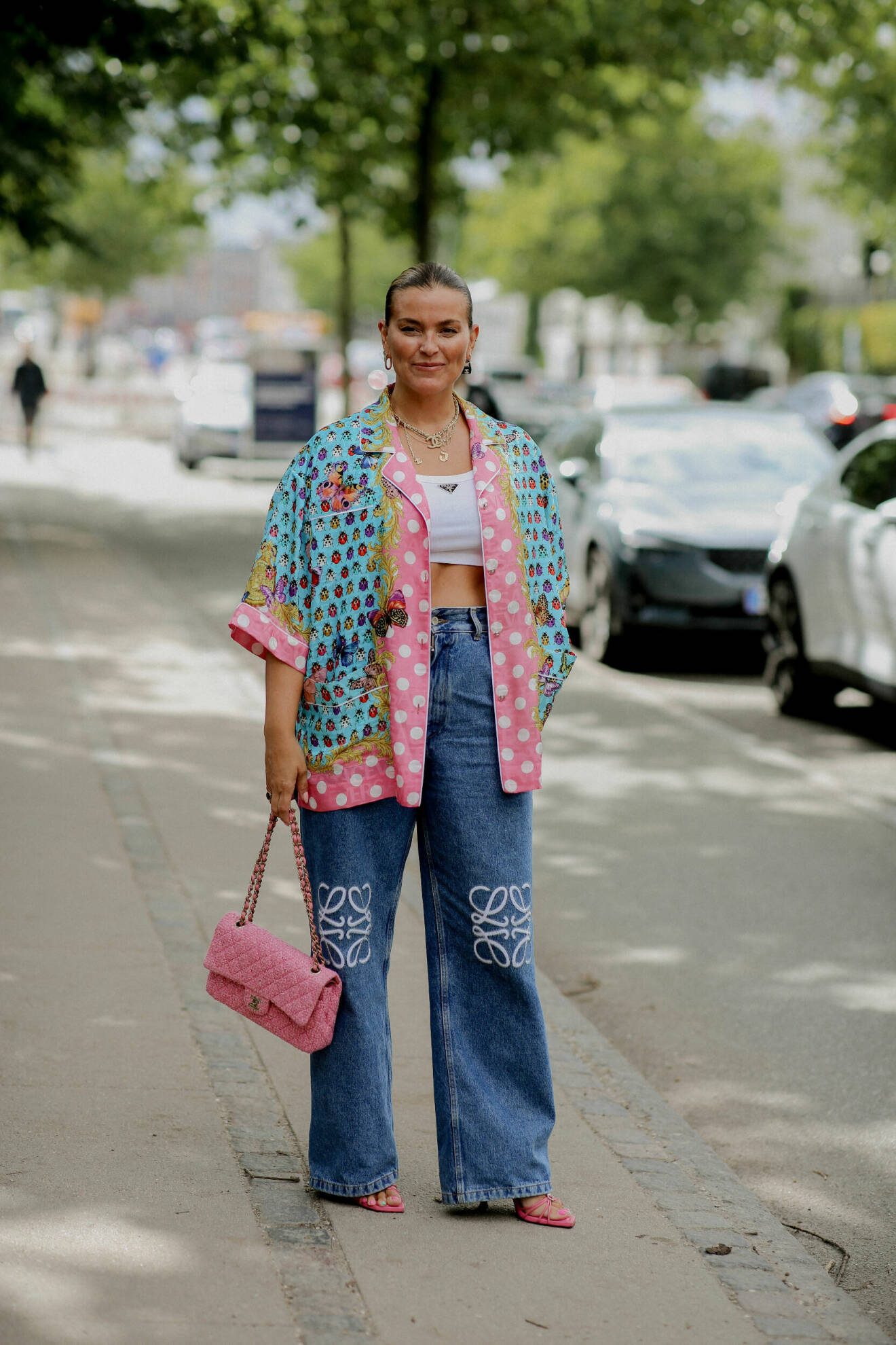 Janka Polliani i en outfit med en mönstrad jacka i blått, grönt och rosa, rosa Chanelväska, rosa klackar och vida jeans från Loewe