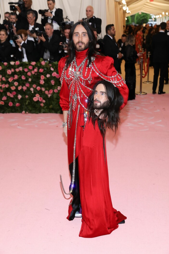 Jared Leto tog med sig en accessoar i form av sitt eget huvud. Foto: TT. Jared Leto i röd maxiklänning från Gucci med strass dekorationer i kedjor på överkroppen. I ena famnen håller han en modell av sitt eget huvud.
