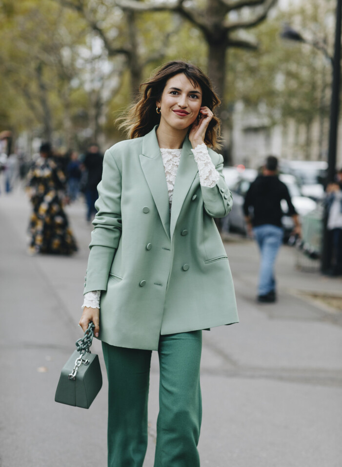 Jeanne Damas bryter av den gröna looken med vit topp. Jeanne Damas i färgkoordinerad klädsel med vit bas
