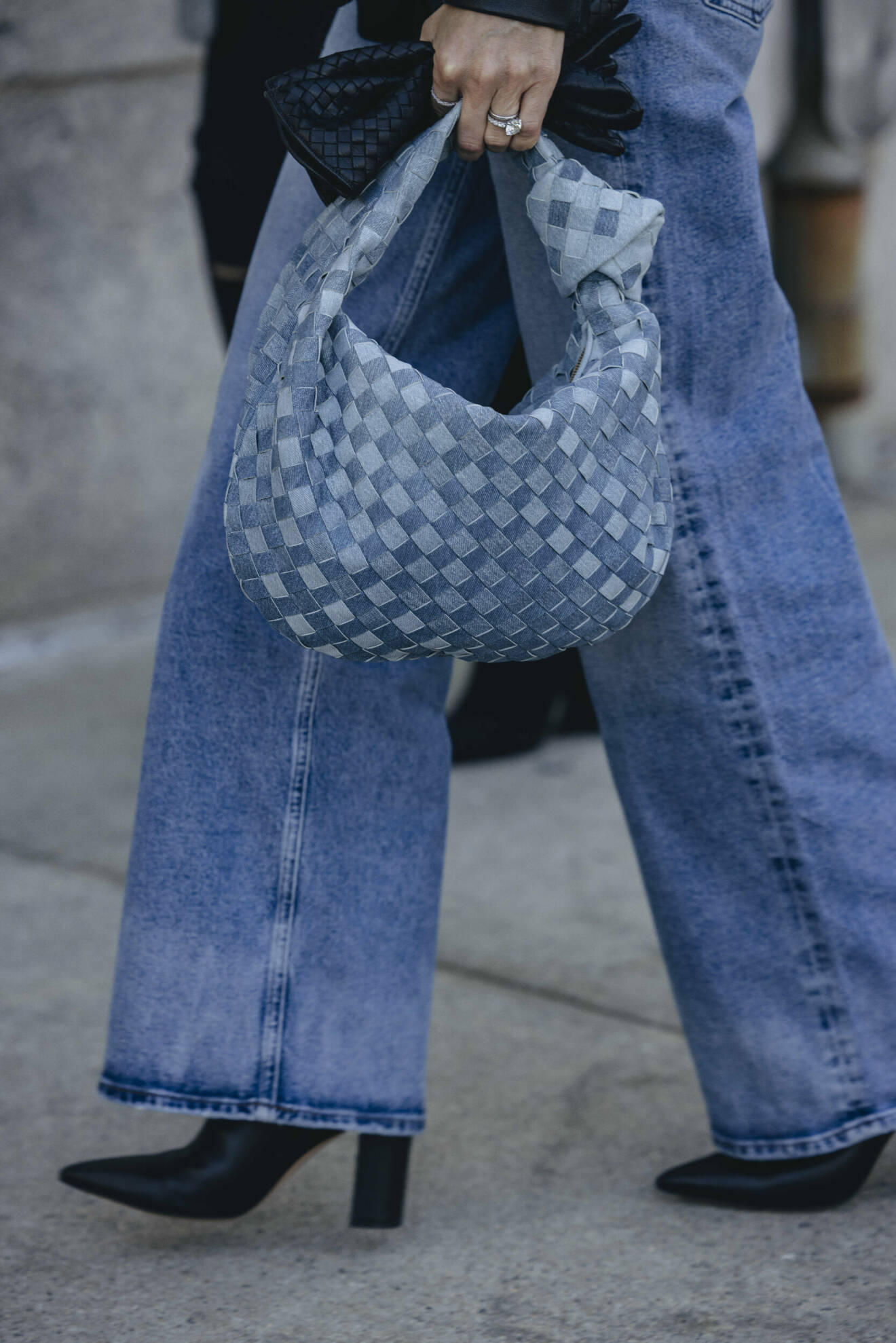Streetstyleoutfit med vida jeans, flätad denimväska och svarta ankelboots