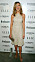 Jennifer Aniston i en beige, glittrig klänning. Klänningen är ärmlös, halterneckskuren och slutar strax nedanför knäna. På fötterna har hon guldfärgade, höga sandaletter med tunna remmar.