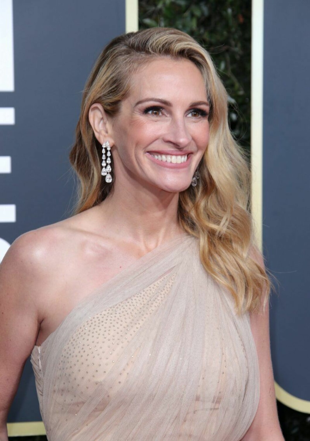 Julia Roberts innan karantän. Julia Roberts är blond och har vågigt hår och ler stort.