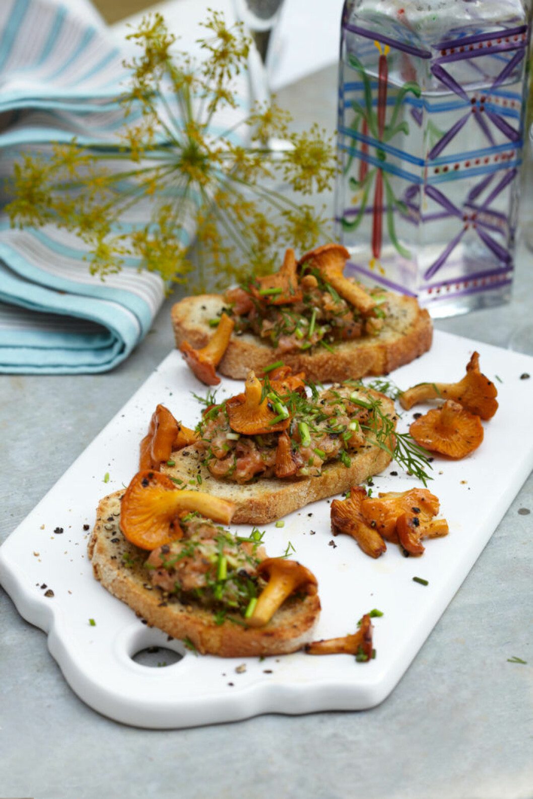 KANTARELLTOAST<br>MED LAXTARTAR KANTARELLTOAST MED LAXTARTAR på vit skärbräda