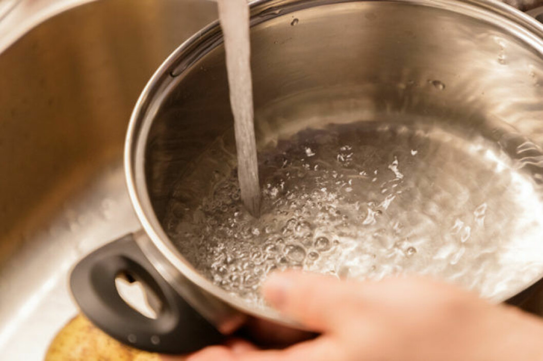 Tänk på att även kastrullens handtag måste klara värmen. Bild: Shutterstock/IBL Person håller i kastrull och fyller med vatten.