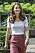 Kate Middleton i vit, ribbad t-shirt och rosa, dressade byxor. Runt halsen har hon ett guldhalsband med tre runda berlocker med första bokstaven i hennes barns respektive namn på.