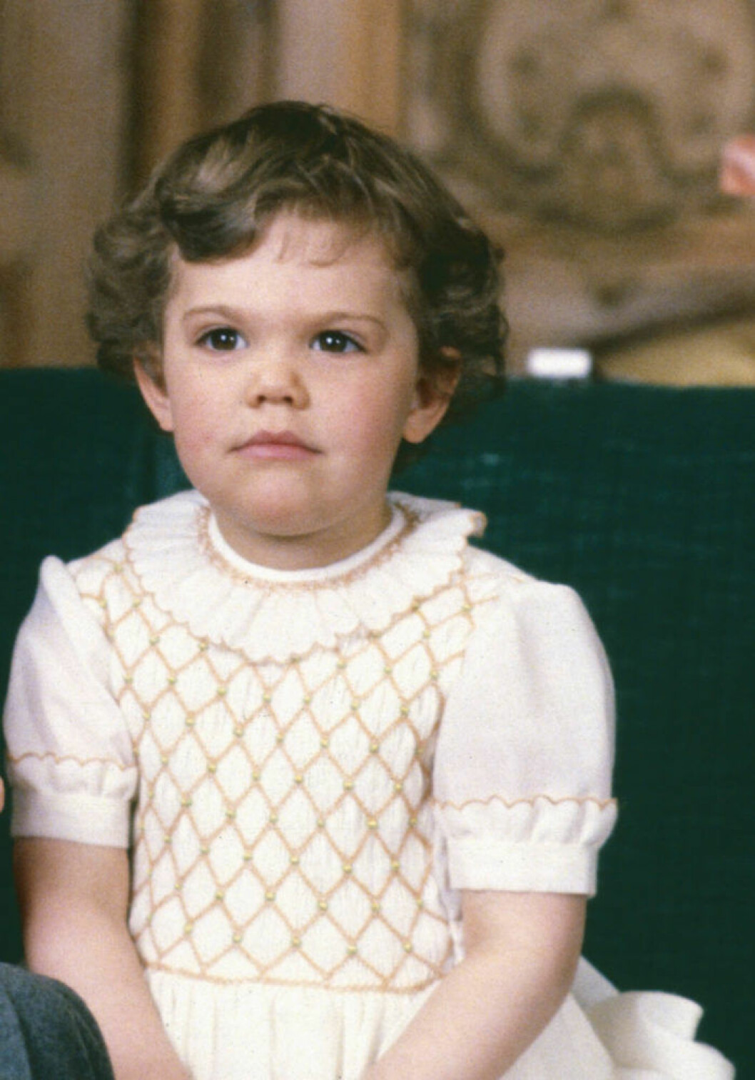 Victoria 1980.<br>När pappa kungen fyllde 34 år 1980 var nyblivna kronprinsessan Victoria knappt tre år gammal. Här sitter hon i soffan på Stockholms slott, iförd sin allra finaste klänning med guldbroderier och en allvarlig min.