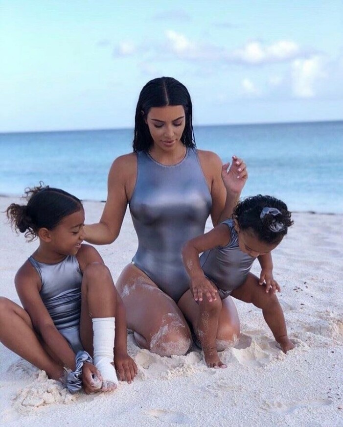 Kim matchar döttrarna North West och Chicago West i silverfärgade baddräkter. Kim Kardashian matchar döttrarna i silverfärgade baddräkter på stranden.
