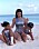 Kim Kardashian matchar döttrarna i silverfärgade baddräkter på stranden.