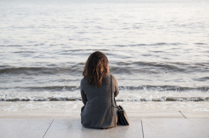 Kvinna sittandes vid havet.