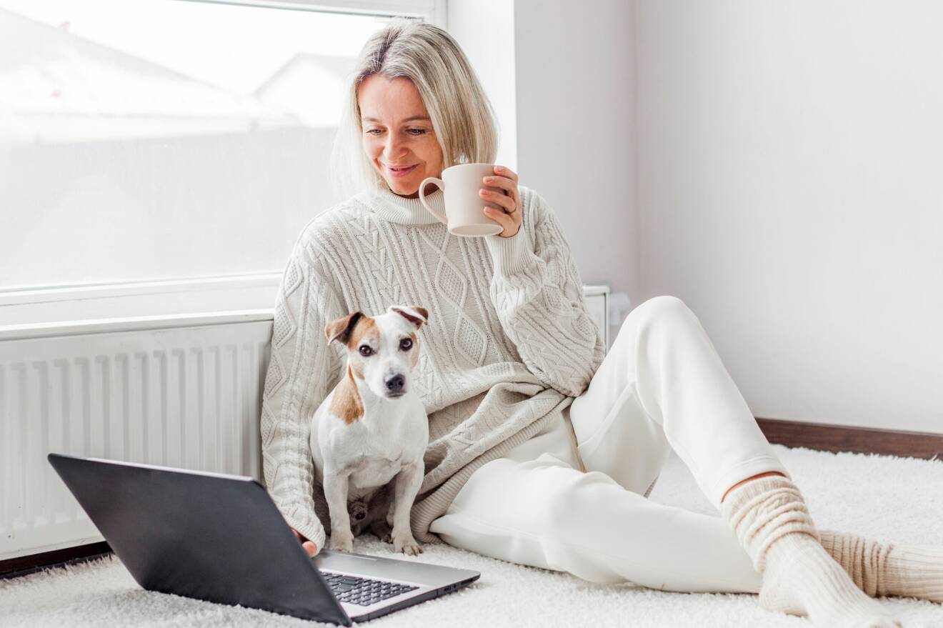 Kvinna i stickad tröja med hund och dator.