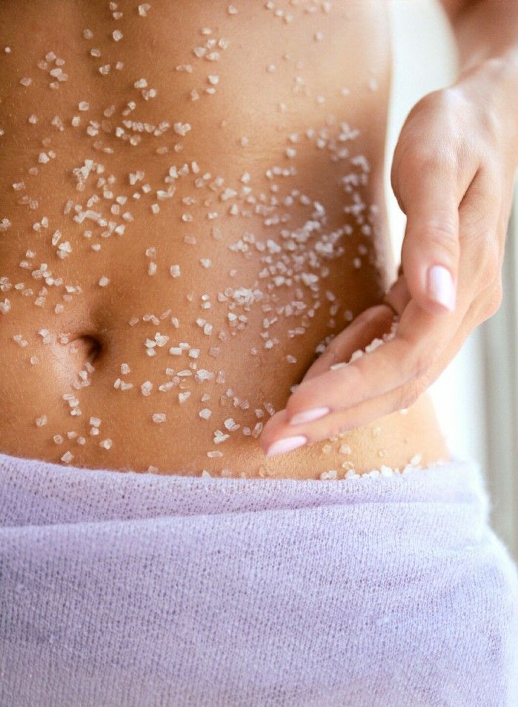kvinna-med-lila-handduk-med-peeling-pa-magen