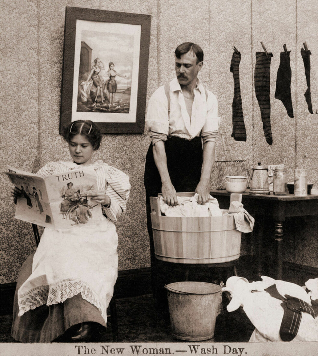 Satir under rösträttsdebatten under tidigt 1900-tal. Foto: TT Kvinna läser tidningen samtidigt som mannen tvättar kläder.