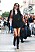 Kendall Jenner i svart, kort skjortklänning och höga svarta boots. På axeln har hon en konjaksfärgad handväska formad som en halvmåne från Staud clothing.