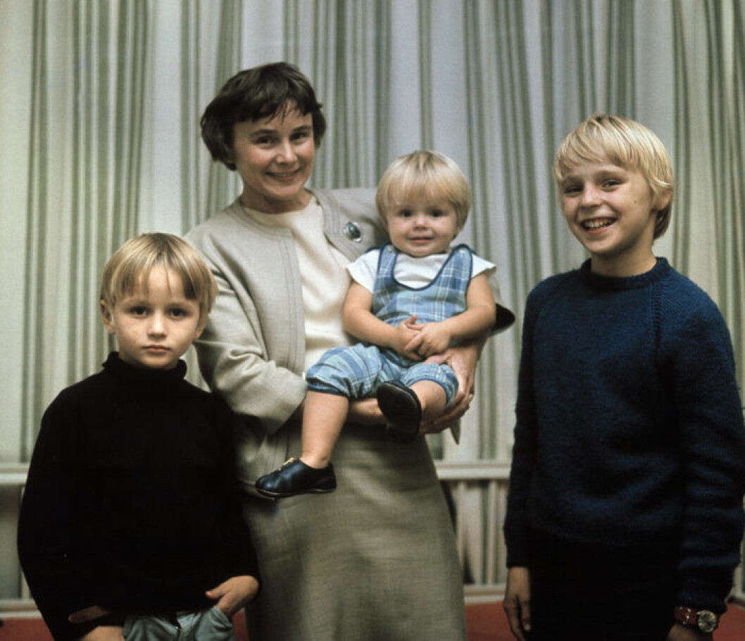 Lisbeth Palme, i radhuset i Vällingby, med barnen Mårten, 7 år till vänster, Mattias 16 månader och Joakim 11 år. Några timmar tidigare har maken och pappan Olof Palme blivit socialdemokratisk partiledare och statsminister. Lisbeth Palme håller sonen Mattias i famnen och Mårten och Mattias står bredvid henne på varsin sida