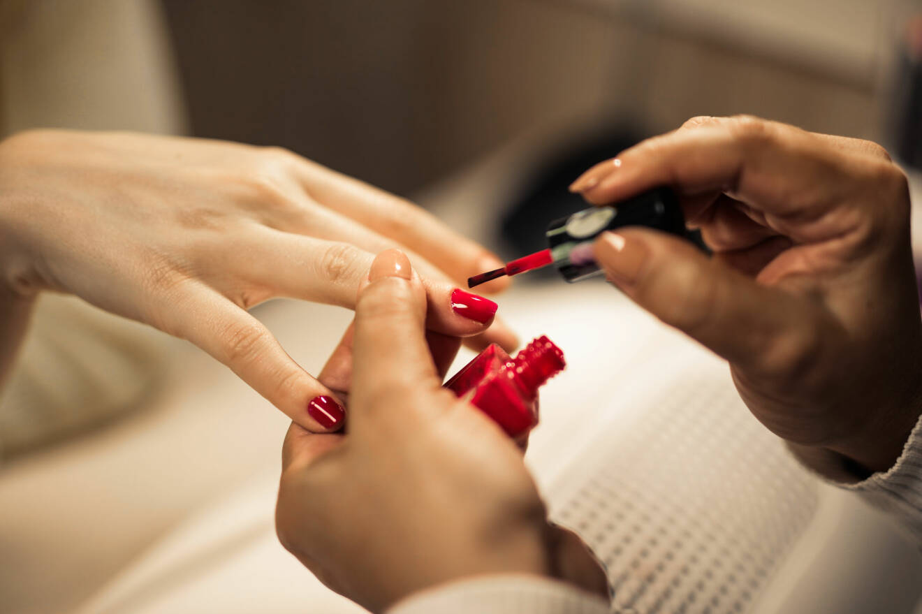 Kvinna målar naglarna i rött.