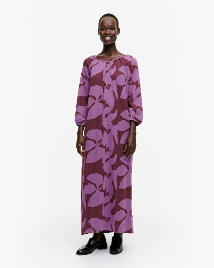 Klänning, Marimekko. Modell med maxiklänning/kaftan i vinrött med lila blommönster på. Klänning från Marimekko.