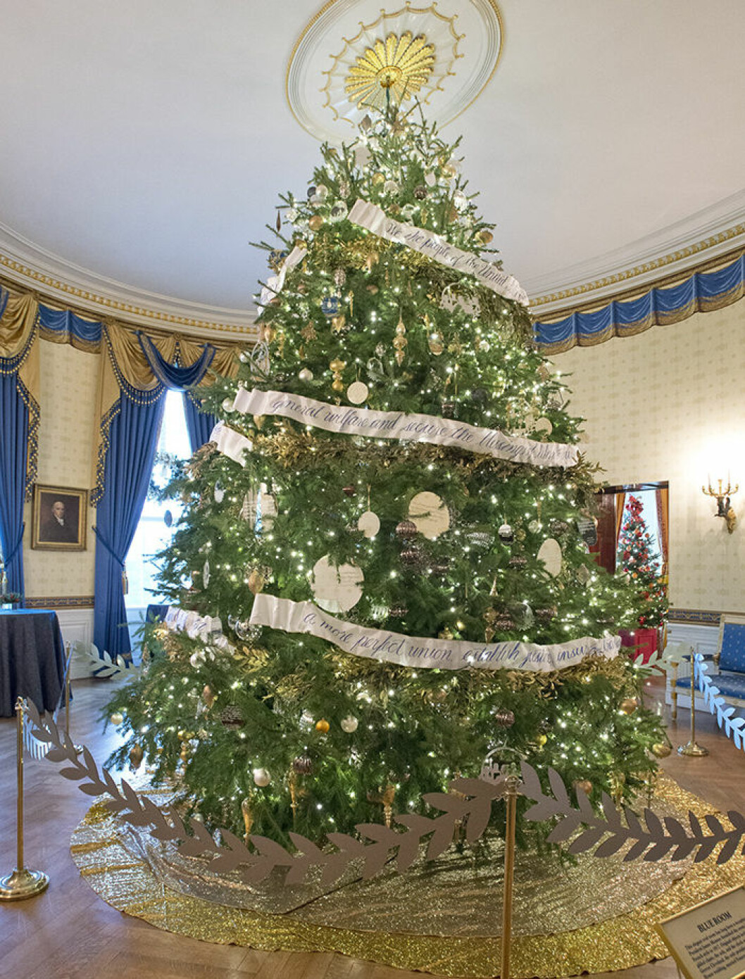 Vita husets officiella gran i Blue Room är över 5 meter hög och klädd i dekorationer i silver och guld. På girlanden i metall står inledningen av konstitutionen. Foto: DPA / IBL Bildbyrå The 2016 White House Christmas decorations are previewed for the press at the White House in Washington, DC on Tuesday, November 29, 2016. Pictured is the Official White House Christmas Tree in the Blue Room. The first lady's office released the following statement to describe those decorations, "This year?s holiday theme, 'The Gift of the Holidays,' reflects on not only the joy of giving and receiving, but also the true gifts of life, such as service, friends and family, education, and good health, as we celebrate the holiday season." Credit: Ron Sachs / CNP - NO WIRE SERVICE - Photo: Ron Sachs/Consolidated/dpa (c) DPA / IBL BildbyrÂ