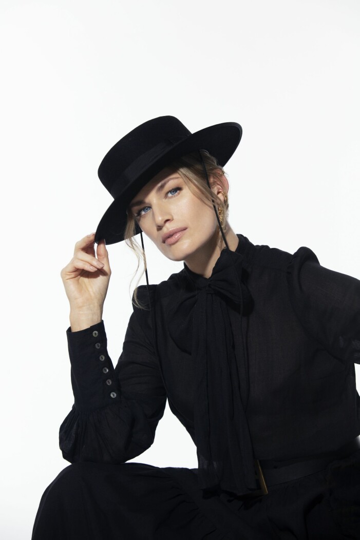 Blus i rami/bomull, XS–XL, 2 699 kr, Nygårdsanna. Kjol i rami/bomull, XS–XL, 3 799 kr Nygårdsanna. Bälte i läder/metall, 1 499 kr, By Malina. Hatt, 1 275 kr Tonak/ Hattbaren NK. Örhänge i guldpläterat silver, 2 095 kr, Maria Nilsdotter. Ear cuff i guldpläterat silver/svarta stenar, 1 495 kr, Maria Nilsdotter. Ear cuff i mässing, 750 kr, Cornelia Webb. Nygårds Svart blus med tillhörande rosett kombinerat med en svart hatt