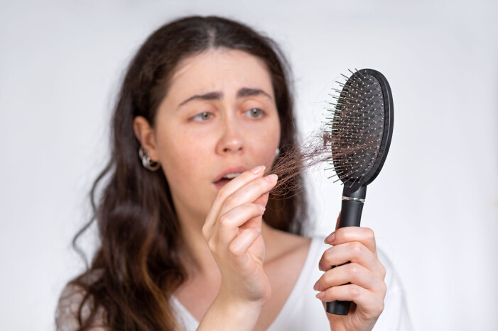 Dags att rengöra hårborsten? Här drar en kvinna ut hår från en smutsig hårborste.