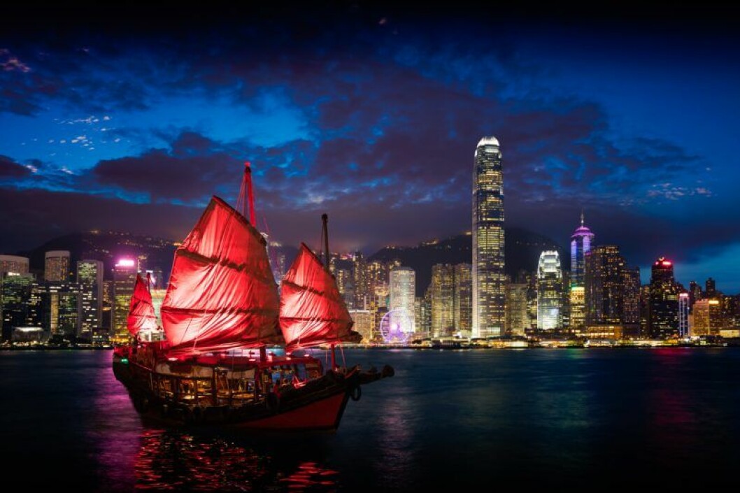 Hong Kong på kvällen med asiatisk röd båt