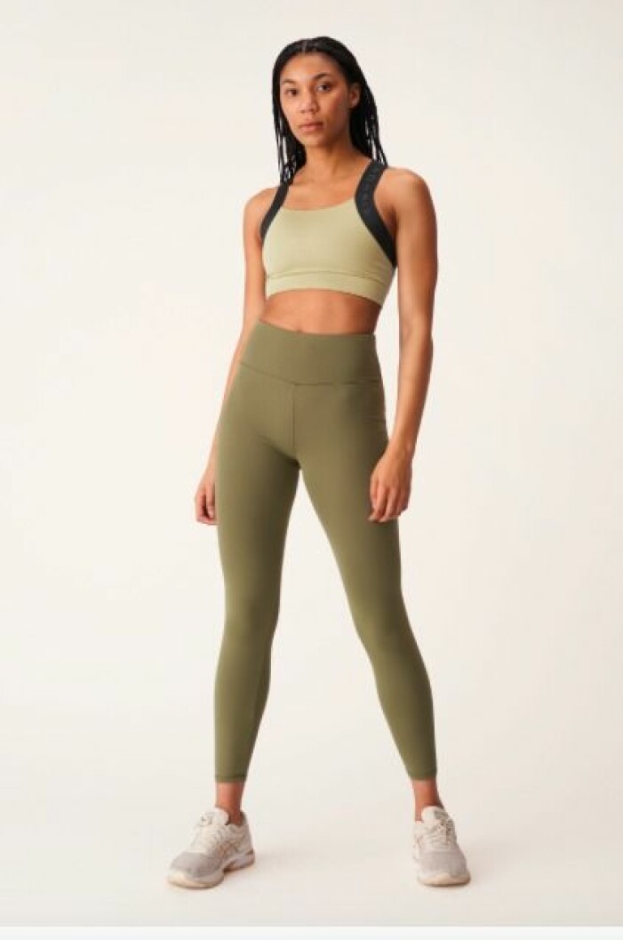 Topp och tights, Röhnisch. <a target="_blank" rel="nofollow" href="https://www.awin1.com/cread.php?awinmid=12441&awinaffid=439045&clickref=an-traningsset&platform=dl&ued=https%3A%2F%2Fwww.rohnisch.com%2Fse%2Fsv%2Fproduct%2Fkay-sports-bra-slate-green-301058S260.html%23accept">Klicka på bilden för att komma direkt till produkterna!</a> Modell med sporttopp och träningstights i olika gröna nyanser. Toppen är ljusgrön med svarta resårdetaljer och tightsen är olivgröna. Set från Röhnisch.