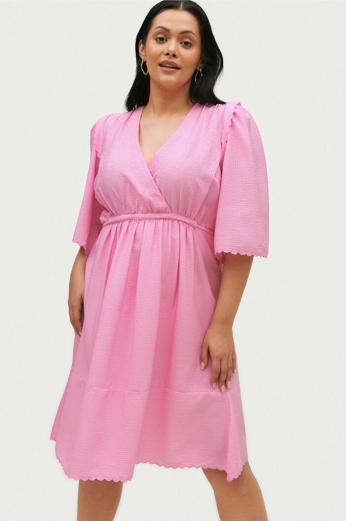 Rosa plus size-klänning från Vero Moda Curve. <a target="_blank" rel="nofollow" href="https://ellosse.sjv.io/c/2867640/1021212/13369?subId1=FE-mod-ALSW-plussize-veromoda-rosa-&u=https%3A%2F%2Fwww.ellos.se%2Fvero-moda-curve%2Fklanning-vmelise-3-4-sleeve-blk-dress-curve%2F1684094-01">Klicka på bilden för att komma direkt till klänningen</a>. rosa omlottklänning i större storlekar och plus size från Vero Moda Curve sommaren 2022