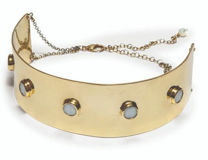 Halsband, Sägen. Bred guldfärgad halschoker i i stel modell. Vita runda detaljer på. Halschoker från Sägen.