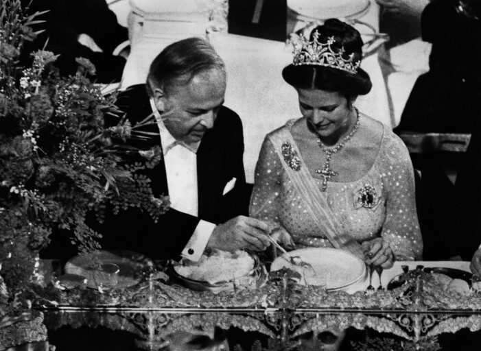 Nobelpristagaren i fysik Burton Richter placerar sin sked i drottningens tallrik. Burton Richter stoppar ned sin sked i drottning Silvias tallrik vid Nobelfesten.