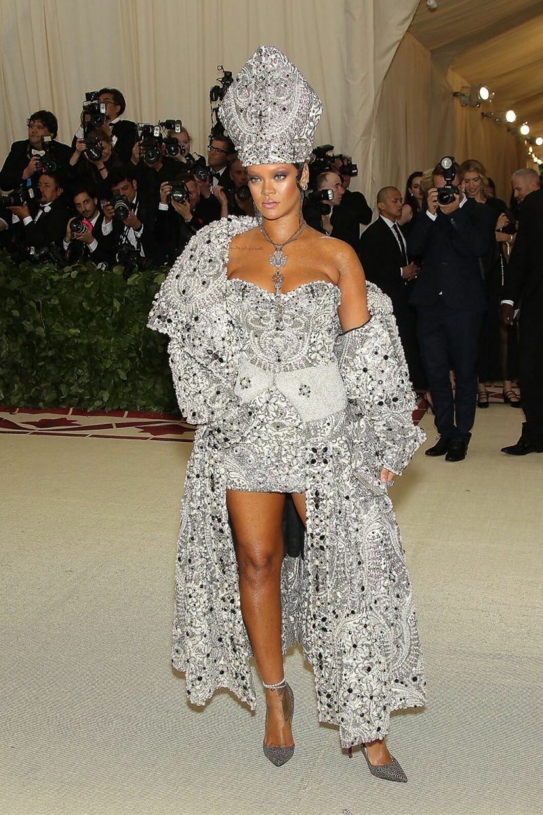 Rihanna i en outfit som efterliknar påvens. Rihanna poserar kaxigt i en dräkt som efterliknar påvens med en gigantisk mitra.