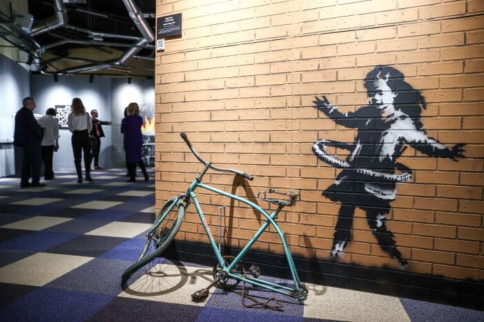 Utställning med Banksys verk 2022. En måladflicka på en tegelvägg, konst av Banksy.