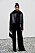 Pritika Swarup i svart shearlingjacka, svarta kostymbyxor och svart väska på Alberta Ferettis AW24-visning under Milanos modevecka.