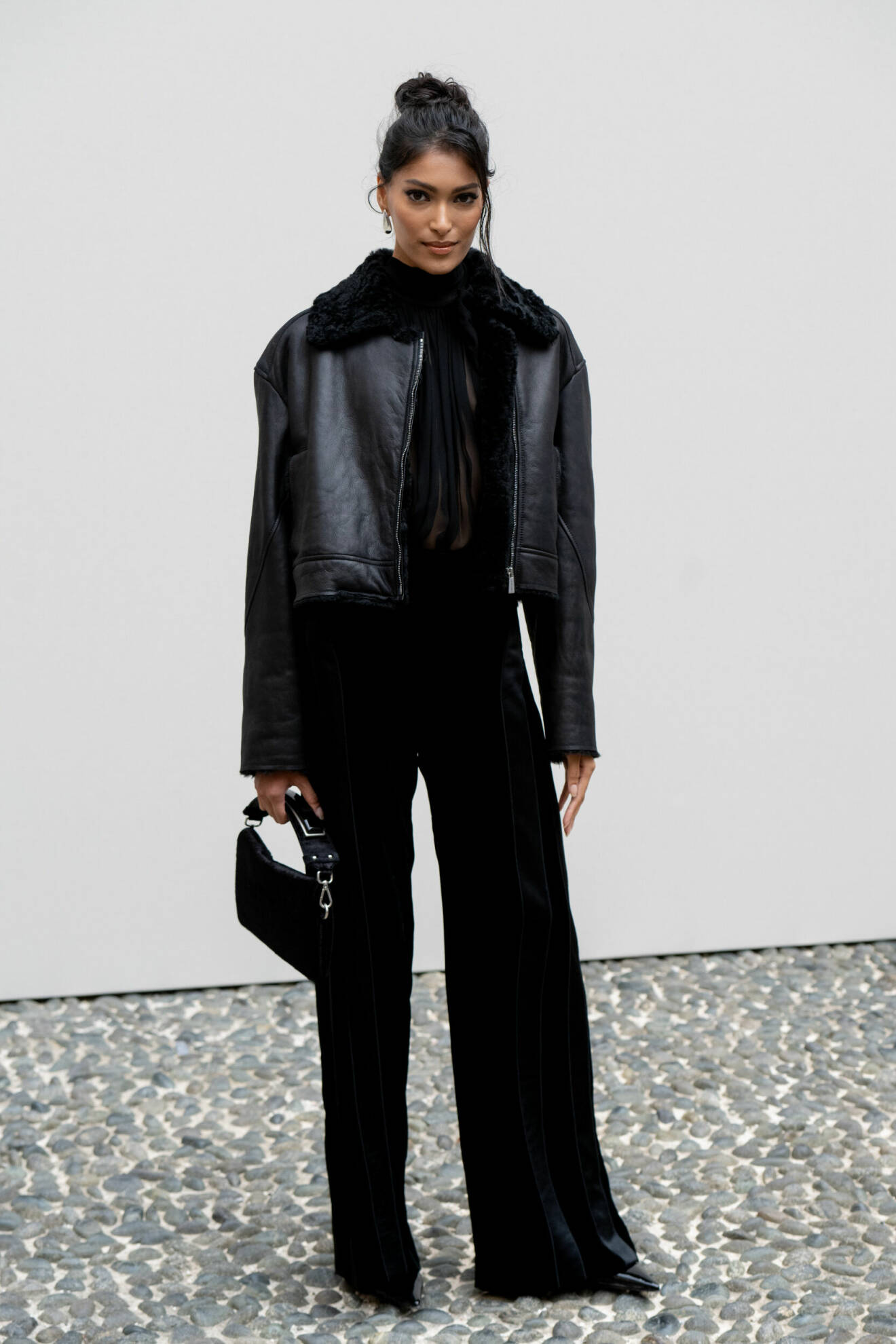 Pritika Swarup i svart shearlingjacka, svarta kostymbyxor och svart väska på Alberta Ferettis AW24-visning under Milanos modevecka.