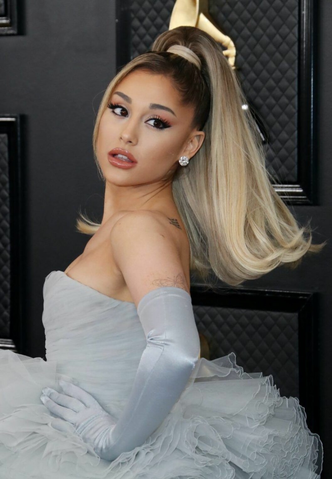 Ariana Grande i hästsvans och grå klänning med handskar