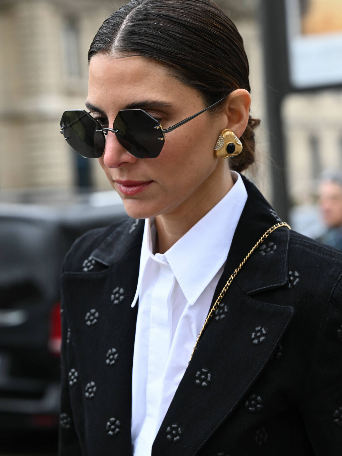 Stilsäker gäst vid Paris fashion week bär trendiga, stora guldörhängen.