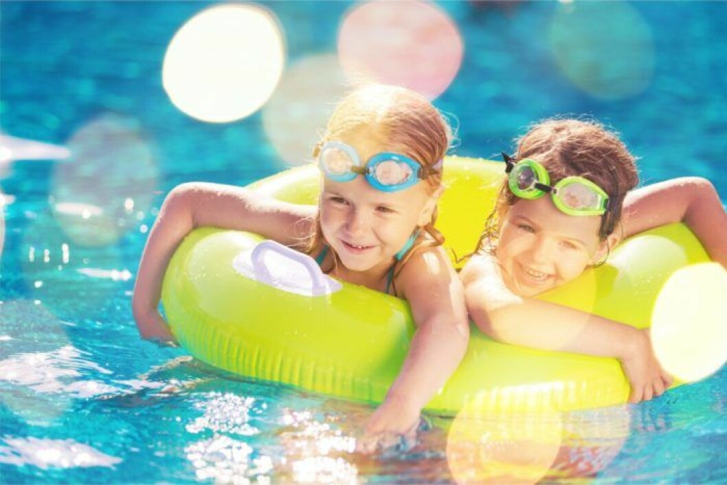 Barn badar och leker i poolen på somamren.