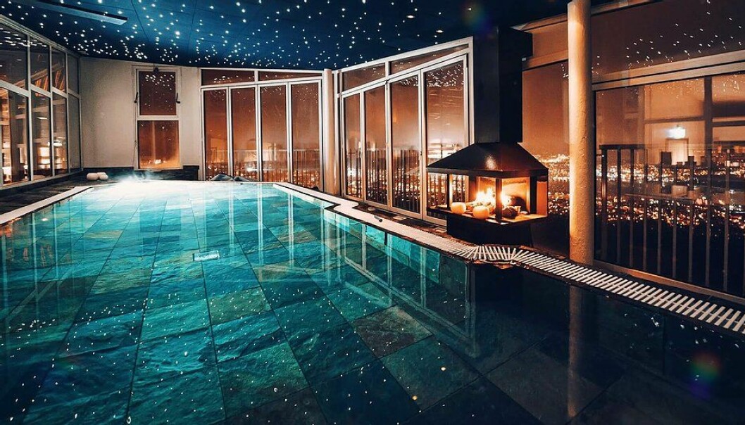 Pool med mysig brasa och utsikt över Sundsvall. en pool inomhus med en brasa som brinner vid sidan