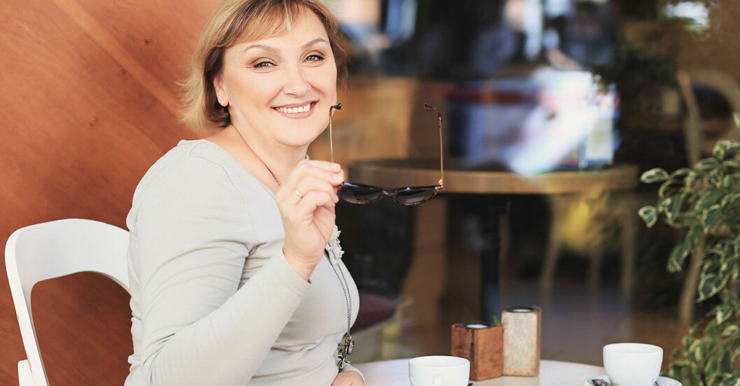 Kvinna sitter på café och dricker kaffe men borde spara pengar
