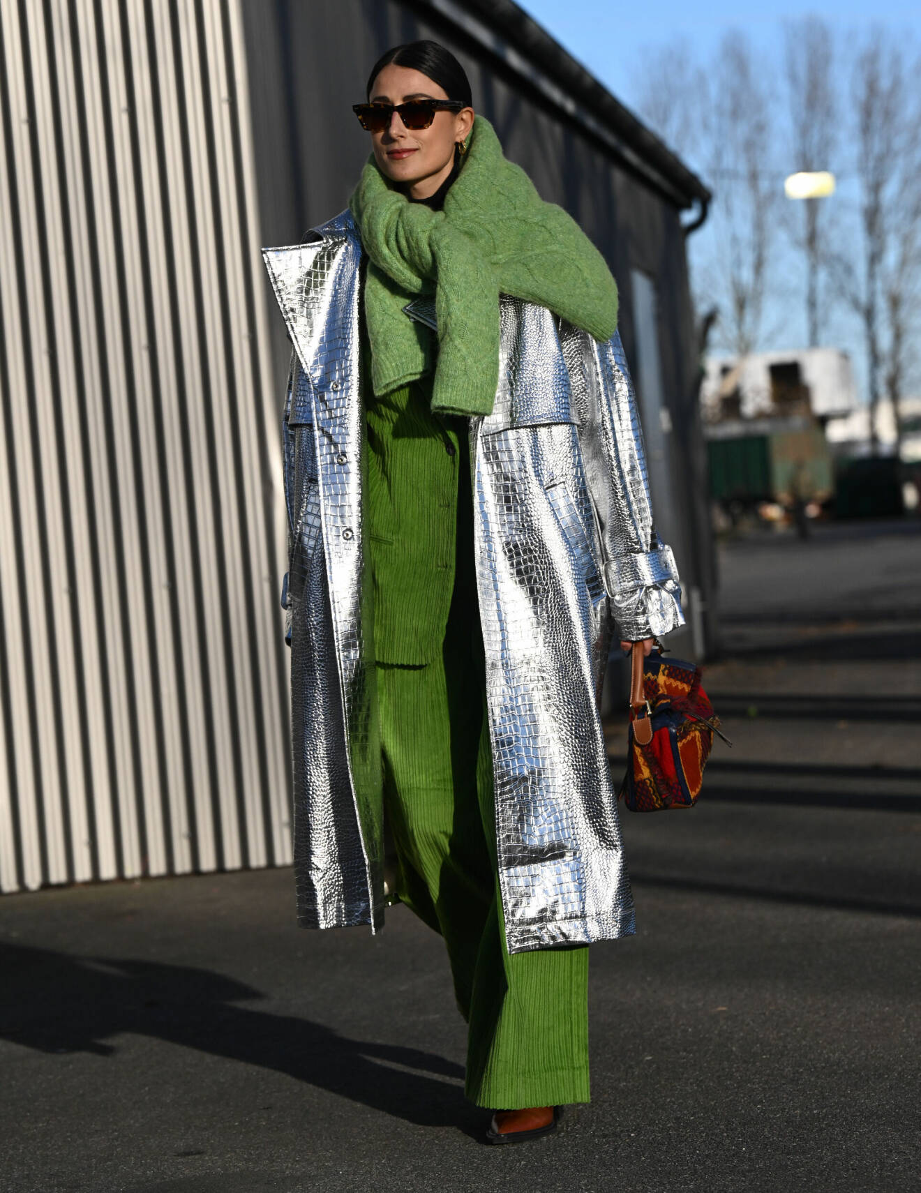 Silverfärgad kappa matchas med grön stickad tröja runt axlarna.